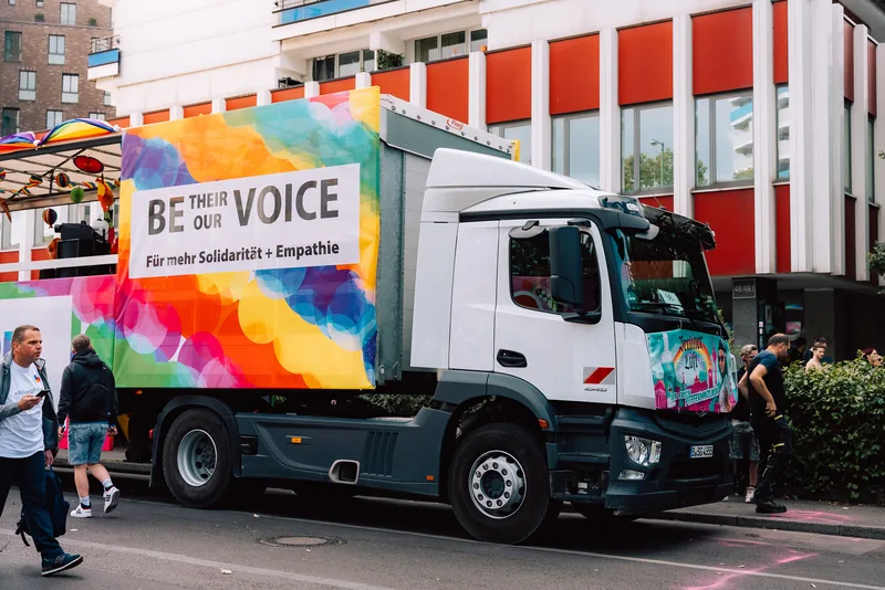 Seitenbanner mit Regenbogen-Motiv und Botschaft auf einem Truck